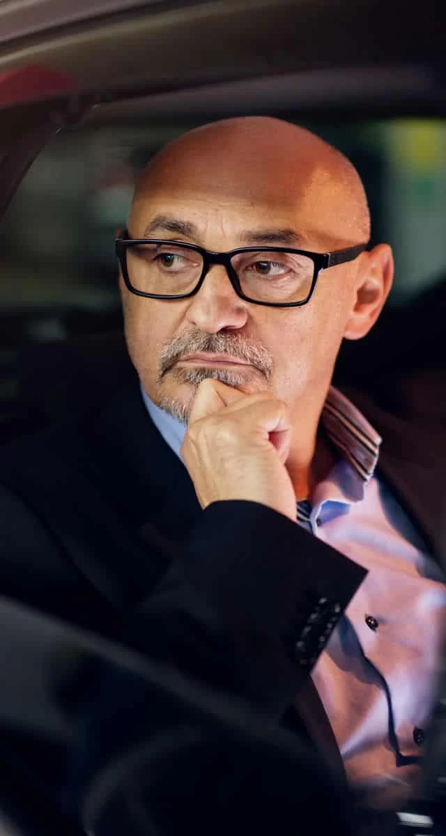 man with glasses looking outside a car window